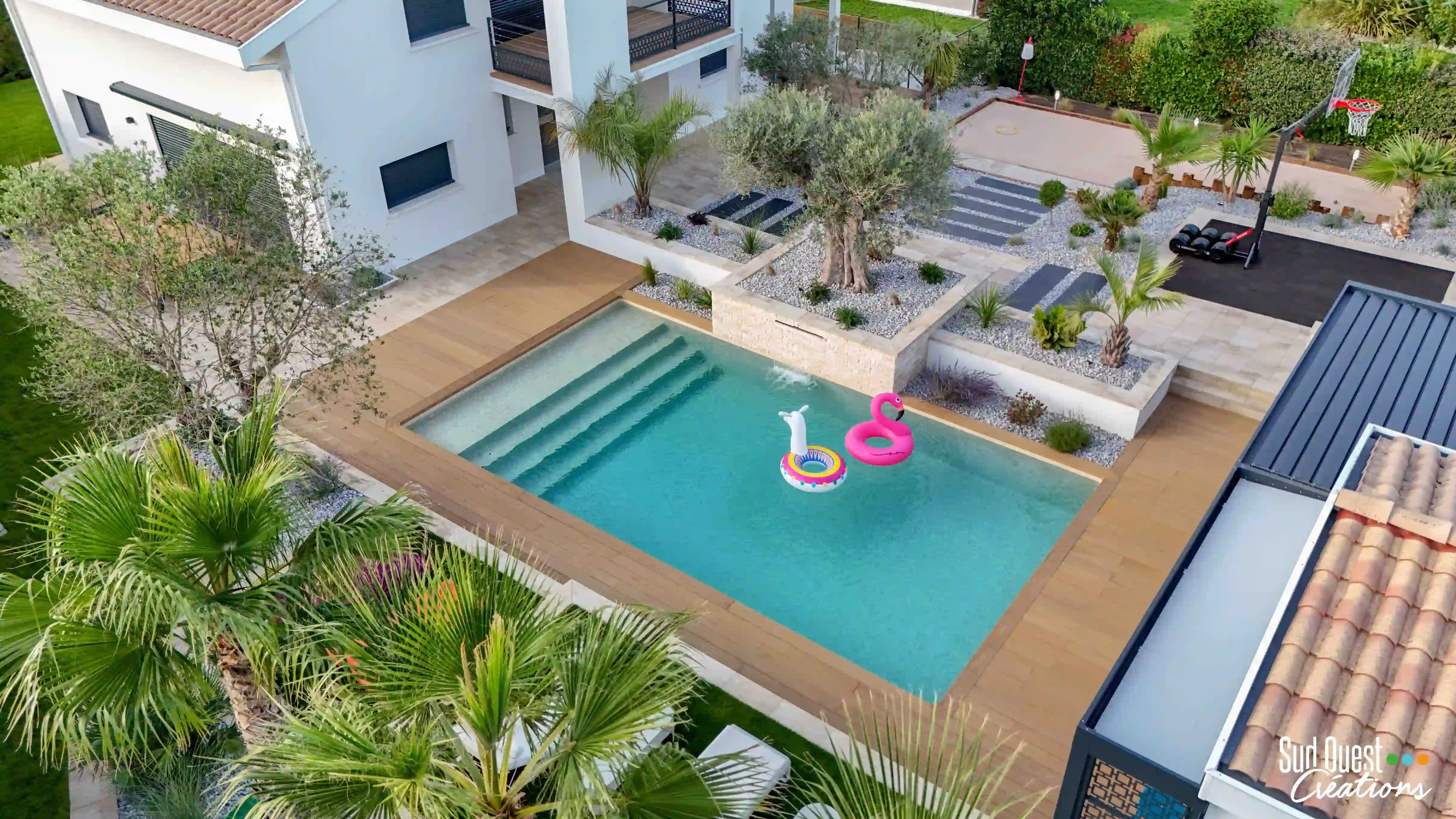 Vue aérienne d'une piscine sur mesure avec terrasse en bois et jardin méditerranéen par Sud Ouest Créations à Toulouse.