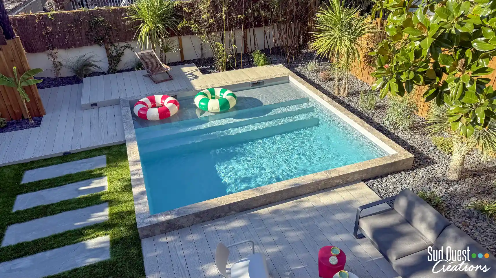Piscine de 5x5m équipée d'une plage immergée (banquette de détente) et d'une terrasse en pierres contemporaines à Léguevin.