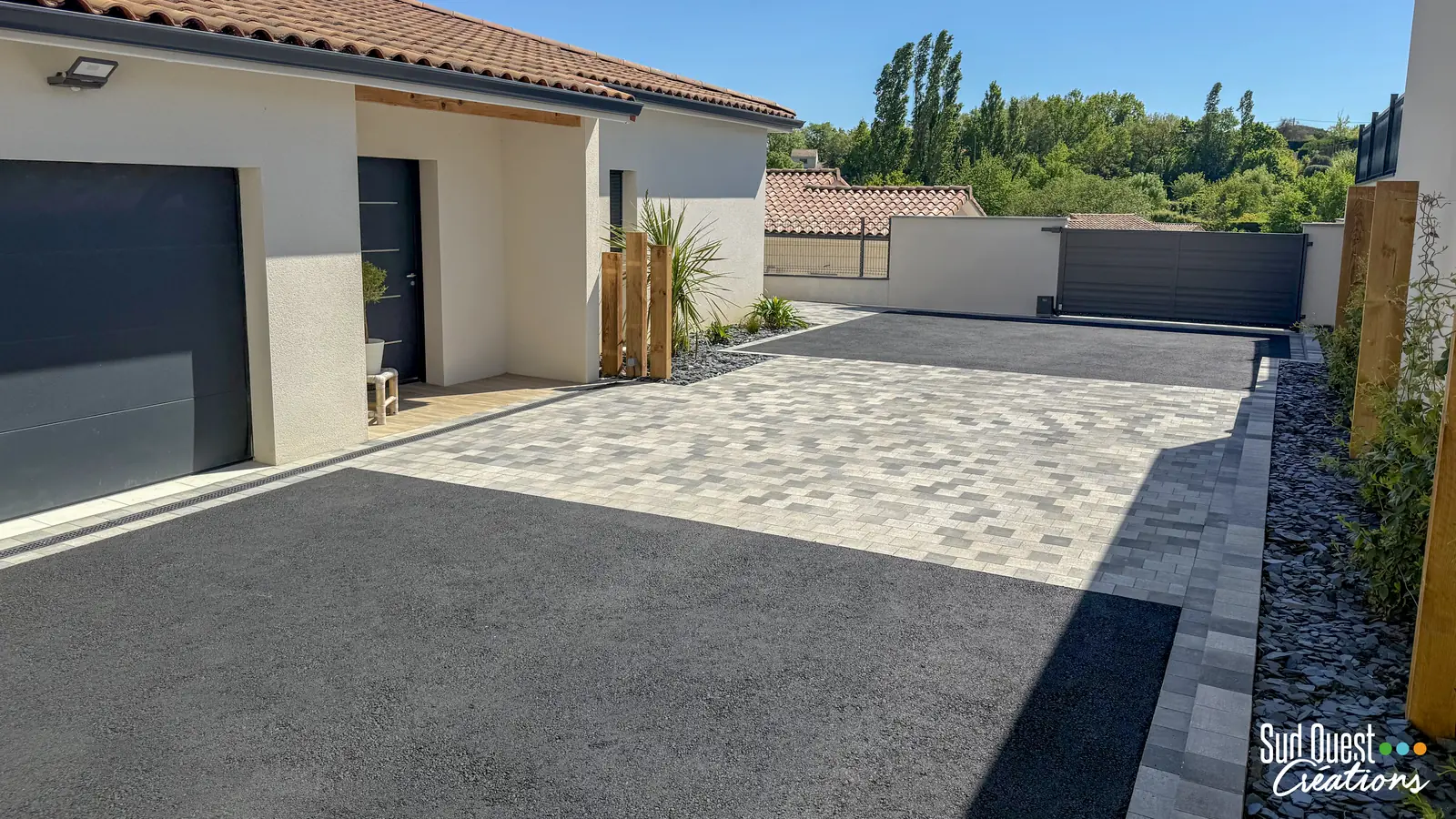 Allée carrossable en enrobé et pavage gris nuancé devant une maison de plain-pied