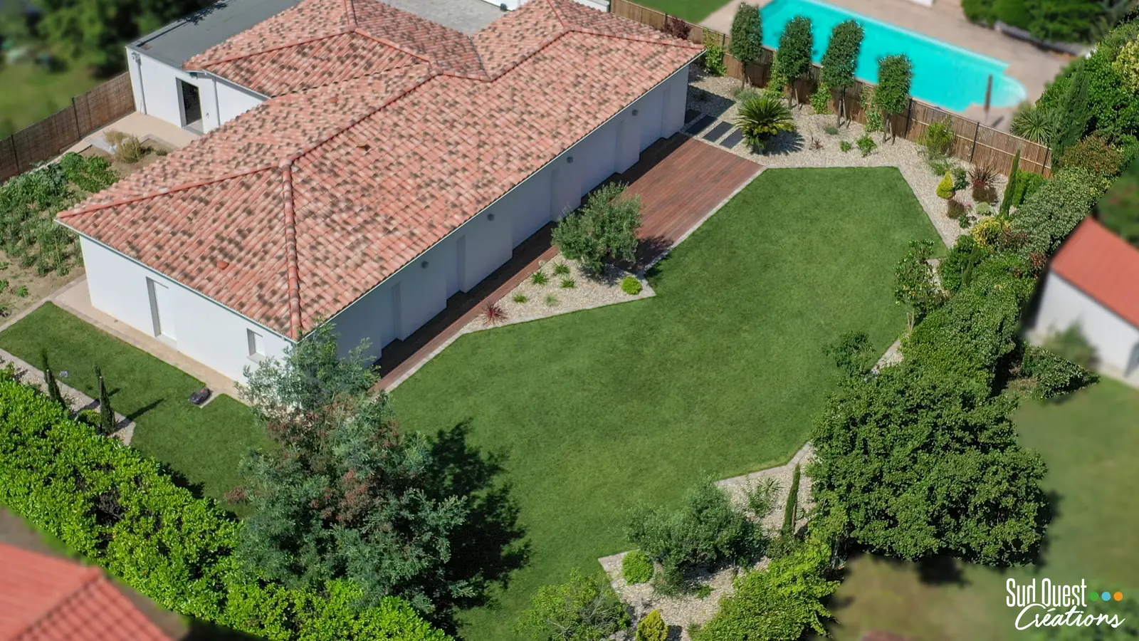 Vue aérienne d'un aménagement de jardin avec grande pelouse, massifs et terrasse en bois