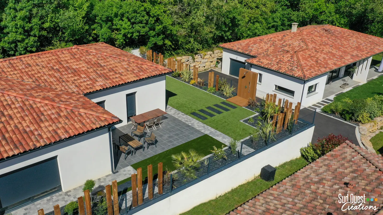 Vue drone d'un jardin de maison de plain-pied : terrasse, gazon synthétique, douche et poteaux bois