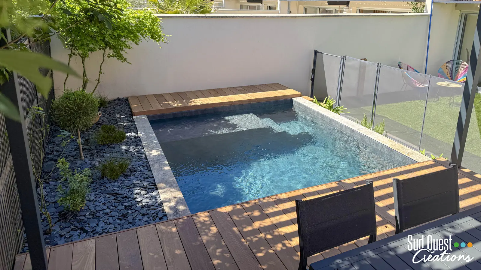 Mini piscine avec margelles en travertin, terrasse en IPE, massif d'ardoise et barrière de sécurité