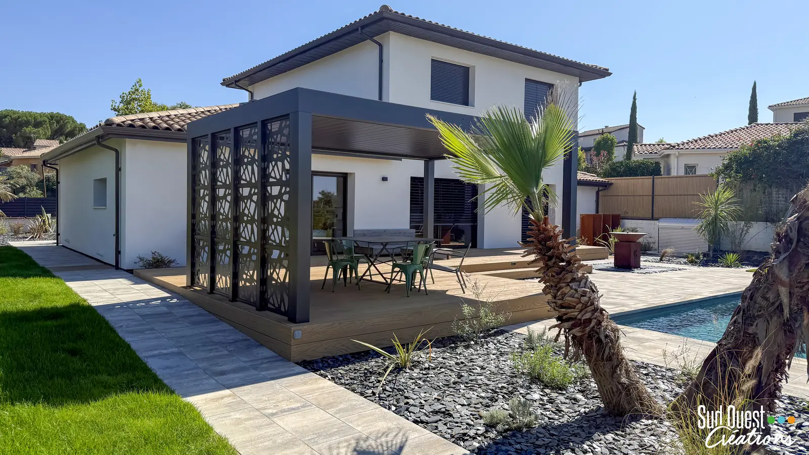 Pergola bioclimatique avec panneaux en métal découpé sur terrasse composite, palmier et massif d'ardoise