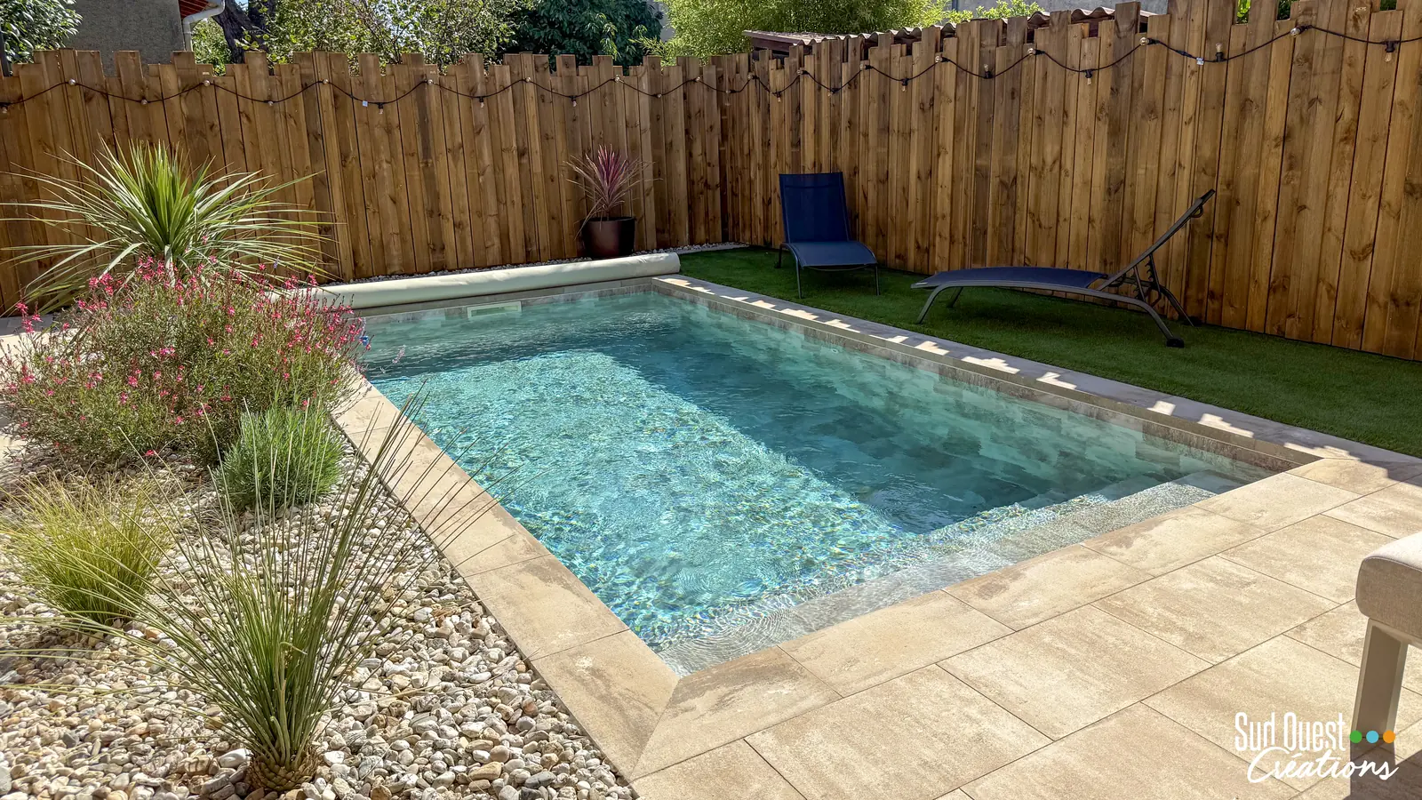Petite piscine avec escalier d'angle, plage en dallage, gazon synthétique et clôture en bois