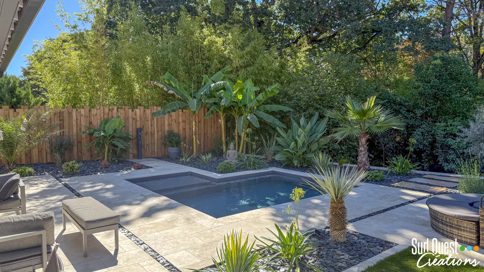 Petite piscine en L avec plage en travertin dans un jardin exotique