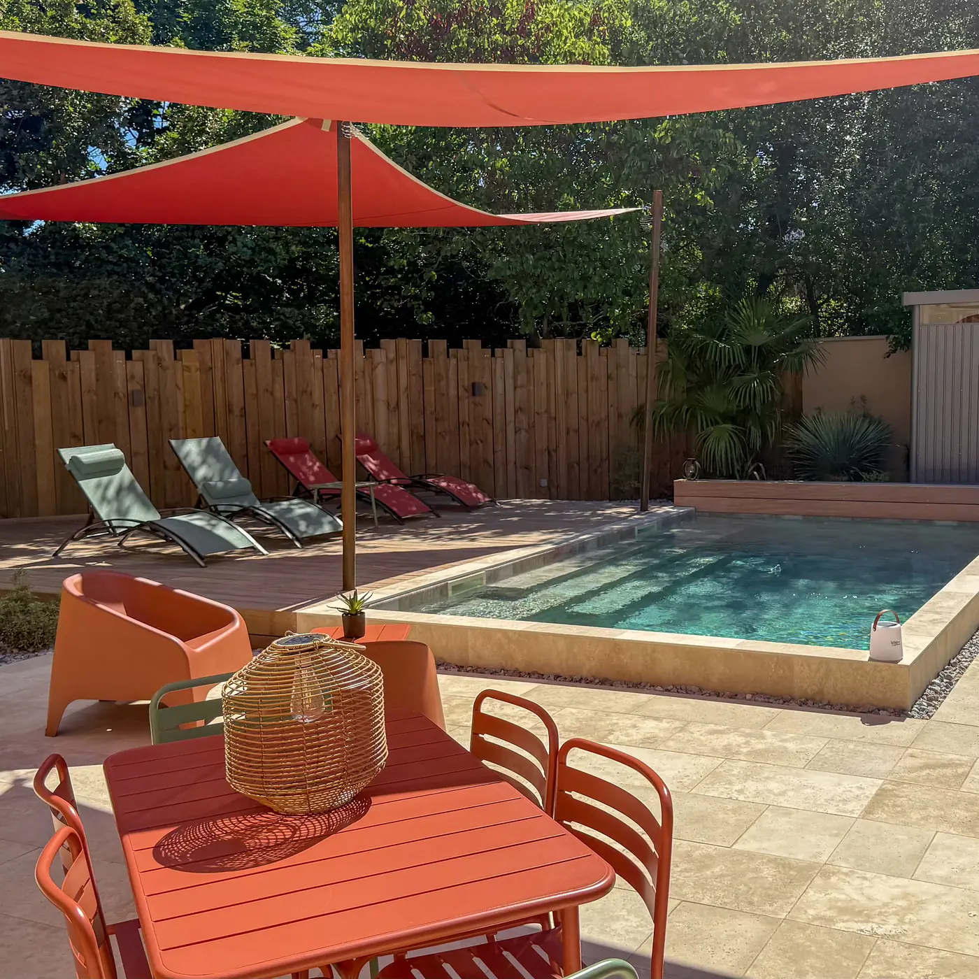 Petite piscine semi-enterrée avec margelles en travertin et terrasse en bois
