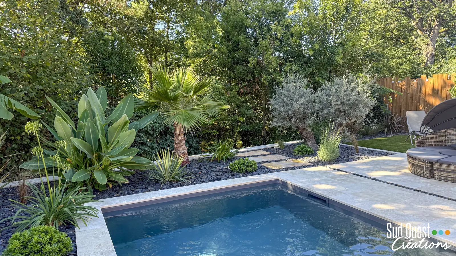 Petite piscine en travertin entourée d'un palmier, d'un olivier et de bananiers