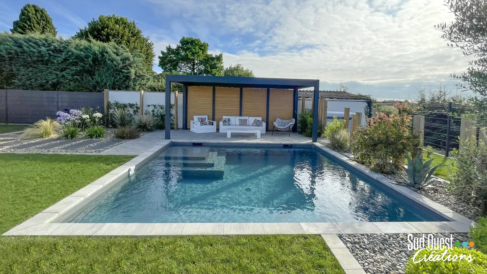 Piscine béton avec pergola aluminium, salon extérieur, massifs de graminées et galets