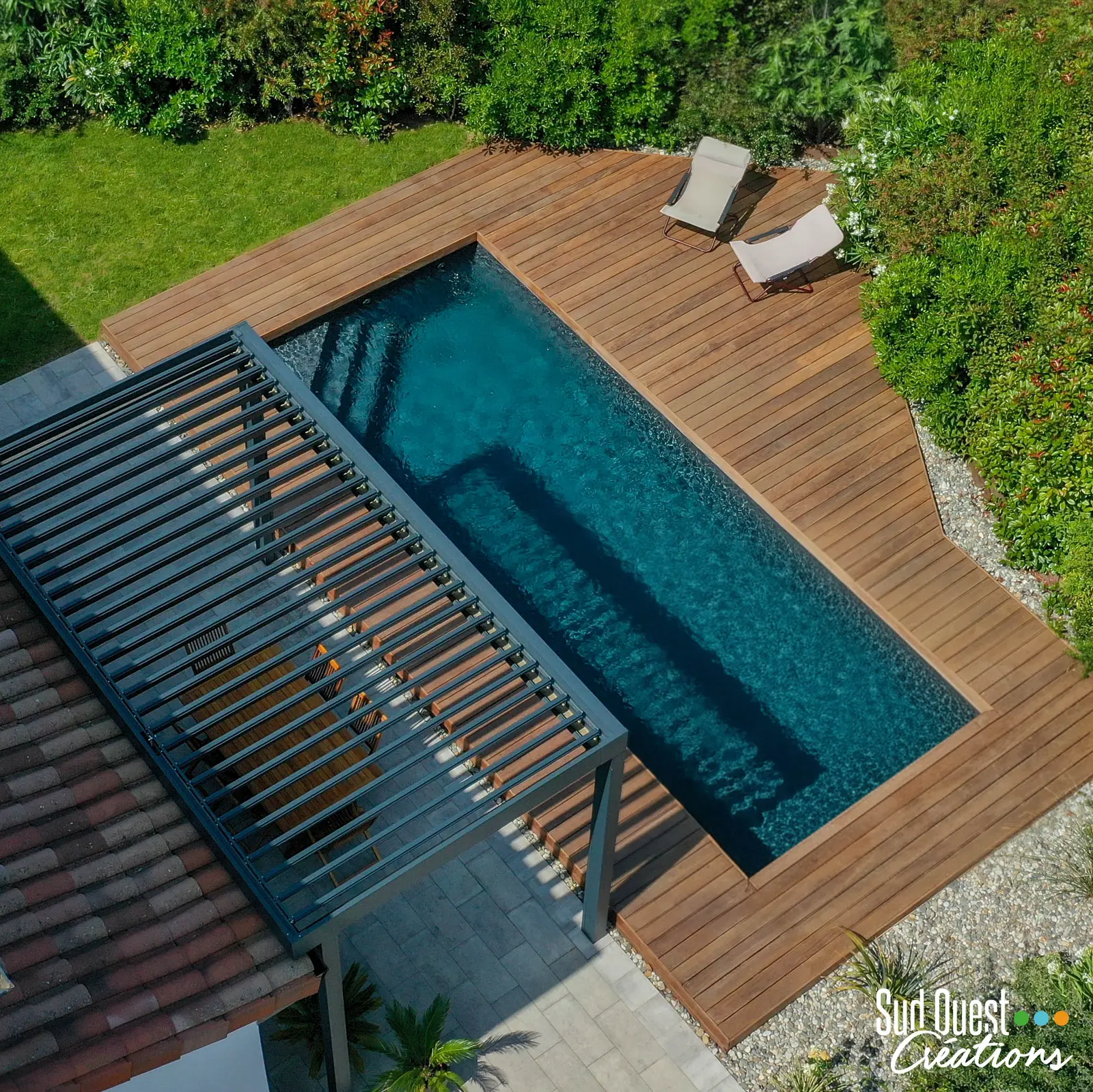 Piscine maçonnée au liner noir avec plage en bois exotique et pergola bioclimatique, vue du ciel