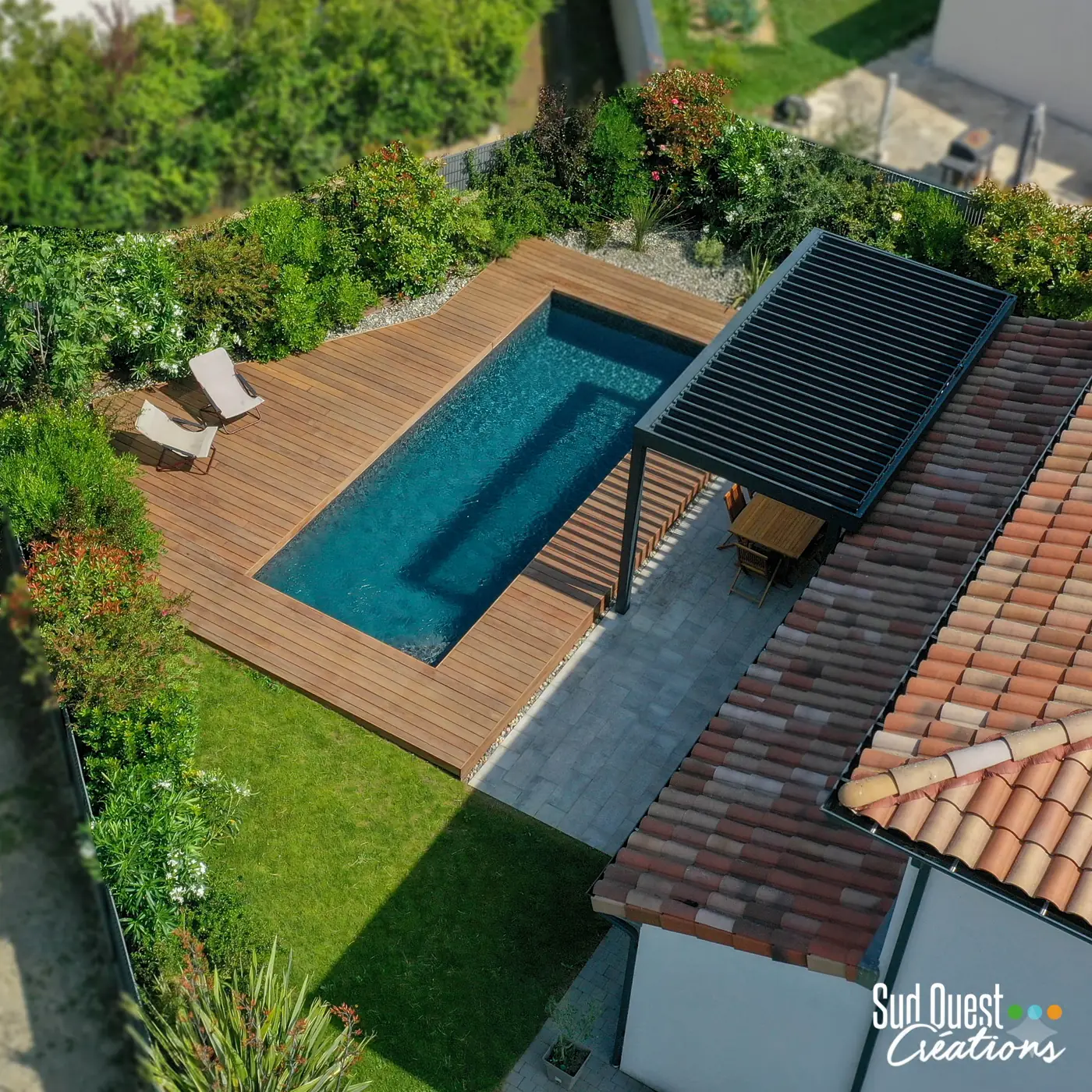 Piscine maçonnée avec terrasse bois, pergola aluminium et jardin planté près de Toulouse