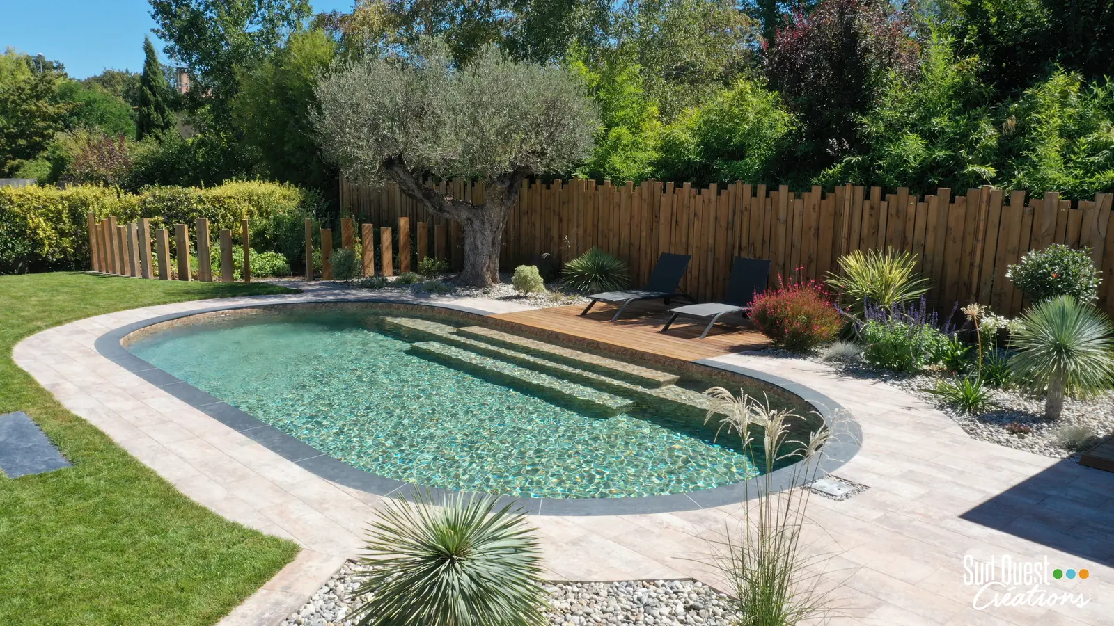 Piscine ovale avec olivier centenaire, plage en bois et clôture en bois