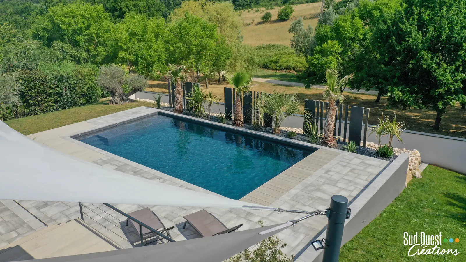 Piscine rectangulaire avec plage en dalles et banquette immergée, face à la campagne
