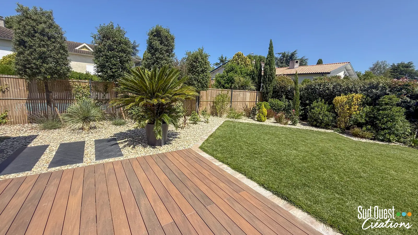 Terrasse en bois exotique, pas japonais en ardoise et massif de galets avec cycas