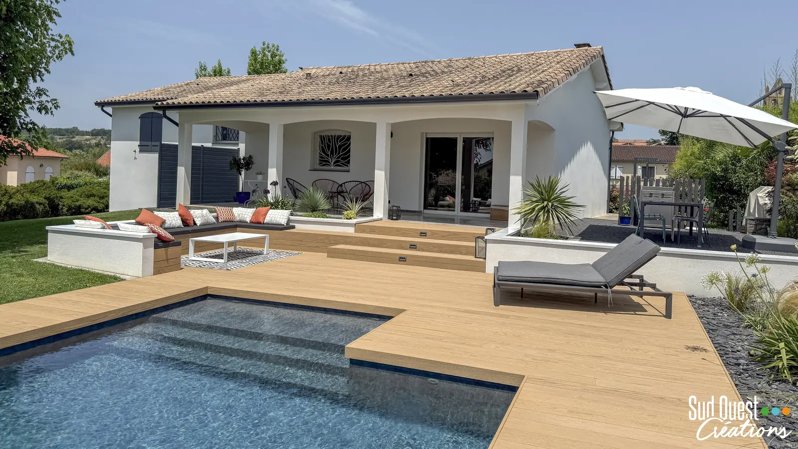 Terrasse composite à escaliers, salon encastré et piscine devant la maison