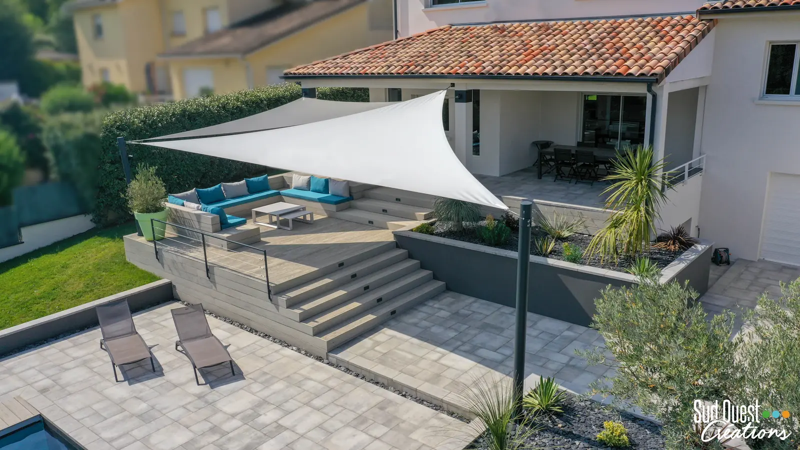 Terrasse composite surélevée avec salon encastré, voiles d'ombrage et large escalier